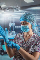 Female nurse in white medical coat, blue mask putting on gloves