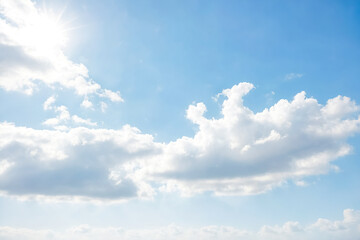 Obraz premium Blue Sky with Fluffy White Clouds and Sun Shining Through