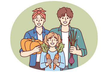 Gardening family posing with organic vegetables grown on own farm and rejoice in good harvest. Happy parents together with daughter are engaged in family business growing vegetables