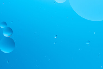 Abstract image with blue bubbles of various sizes on light blue background, creating serene and minimalistic look.