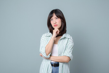Lifestyle, asian woman emotions and casual concept. Shy and modest cute clueless girl, smirk, uncertain, having doubts or hesitations, standing pastel green background