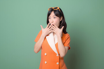 Surprised woman in orange dress with hands over mouth