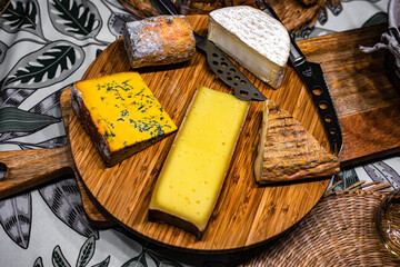 Plateau de fromages servi à table avant le dessert. Plusieurs différents fromages sur la planche en bois et un couteau à fromage.