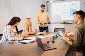 Obraz premium Group of business people sitting in a meeting room discussing a design for a smartphone application.