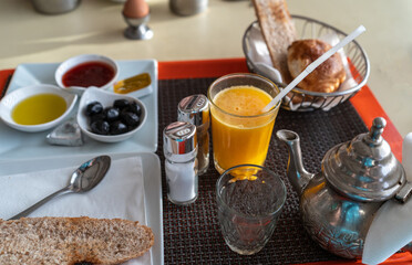 Moroccan breakfast also known as ftour, orange juice, tea, bread, croissant, jam, honey, olives, metal teapot