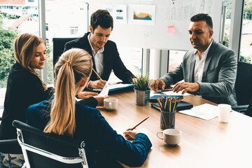 Businessman executive in group meeting discussion with other businessmen and businesswomen in modern office with coffee cups and documents on table. People corporate business working team concept. uds - Powered by Adobe