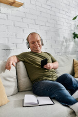 A man with inclusivity wearing headphones relaxes on a couch in his home.