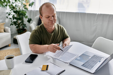 A man with inclusivity sits at a table in his home, looking intently at a document.