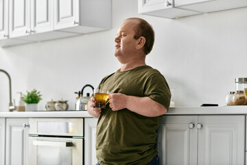 A man with inclusivity stands in his kitchen, casually dressed, enjoying a cup of tea.