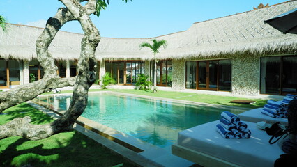 Image of a swimming pool in a villa house resort with Kamboja tree and Palm tree tropical vibe
