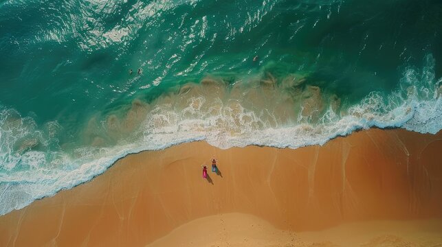 An aerial view of two individuals standing on the beach, overlooking the azure waters with surfboards in hand AIG50
