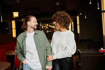 An African American woman and a man stand side by side in a modern cafe, illustrating strength and togetherness.