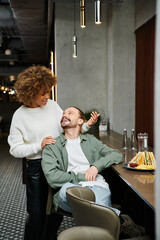 An African American woman and a man sit together in a modern cafe, engaged in conversation and comfortable in each others presence.