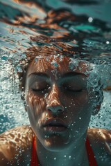 Fototapeta premium A woman is shown underwater wearing a red bikini, providing an unique perspective on the beauty of the ocean and its inhabitants