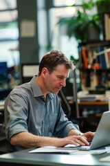 Fototapeta premium A person sitting at a desk with a laptop, possibly working or studying