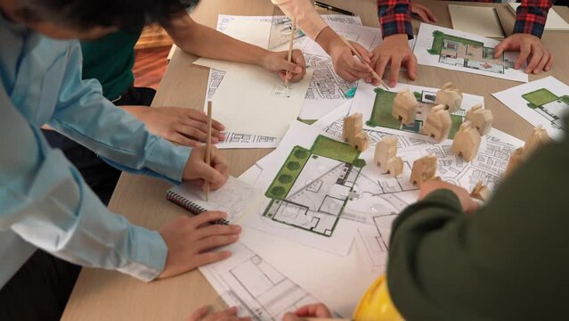 Architect and safety engineer discussion about building construction use blueprint on table with architectural document, measurement tool and wooden block scatter around at modern office. Delineation.