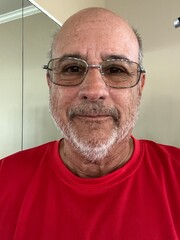 Portrait of a healthy looking male senior citizen wearing a red work out shirt.