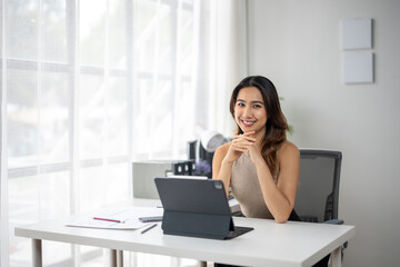 A woman is sitting at a desk with a laptop and a tablet