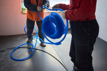 Team of workers collaborating indoors on construction project with blue tubing installation