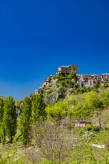 Fototapeta premium A view of the village of Castel di Tora, Rieti, Lazio, Italy. Surrounded by green mountains, it overlooks Lake Turano. The Castle stands at the top of the hill. Blue sky in summer.