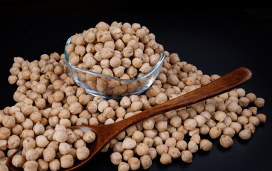 Glass cup with chickpeas. Wooden spoon with chickpeas and chickpeas scattered around.
