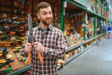 A man chooses garden shears in a hardware store.