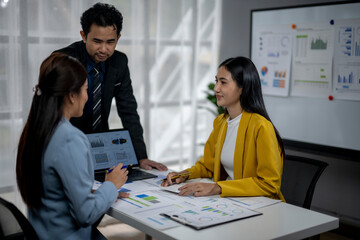 Three people are sitting at a table with a laptop and papers in front of them