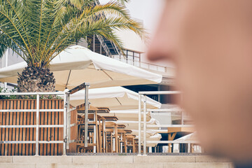 Selective focus on the date palm. In the foreground, a man's face is in close-up. Cafe on the...