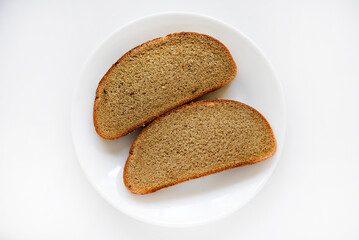 Two pieces of rye bread on a white plate.