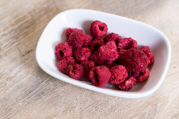 dried raspberries in bowl on wooden floor