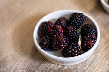 black mulberry in a bowl on the wooden floor