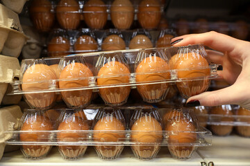 A person is reaching for a carton of eggs