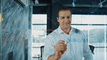 Smart businessman thinking about start up project in front of glass board. Smiling male project...