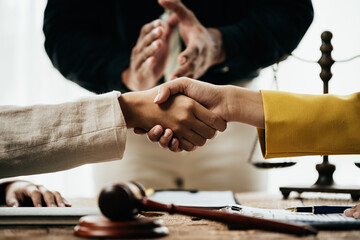 Close up of hands Lawyers explain and discuss matters of law then shakehands after and dealing contract agreement to clients discuss for prepare for the trial. gavel hammer and scales of justice.