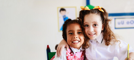Pre school children having fun smiling on camera at kindergarten classroom. Friendship and education concept