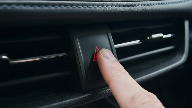 Person turns on a car's hazard warning flasher button, close-up.