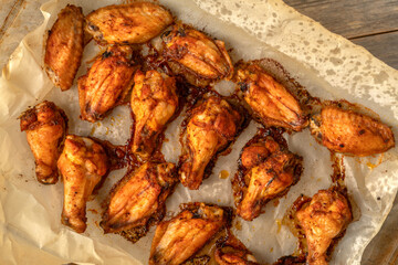 Homemade baked chicken wings in barbecue sauce in a baking dish on a gray wooden table
