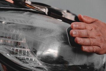 Obraz premium Polishing car headlights on a car. 