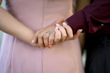 Fototapeta premium bride and groom holding hands behind back wearing pink and burgondy