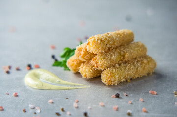 Breaded mozzarella cheese sticks with golden crispy crust on a wooden board. Beer appetizer