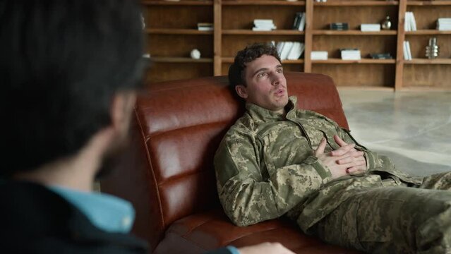 Psychologist talking patient client Caucasian male officer man soldier military army veteran guy lying couch talk psychotherapist analysing psychological war trauma psychotherapy session cabinet room