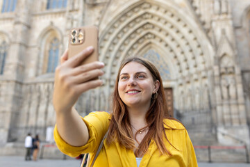 Young traveling woman taking selfie in front of the famous saint Eulalia church in Barcelona. Concept of travel, tourism and vacation in city. Use technology concept, Traveling Europe