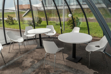 Group of white chairs and tables are arranged in a circle inside a glass dome. The meeting room has a modern and minimalist design