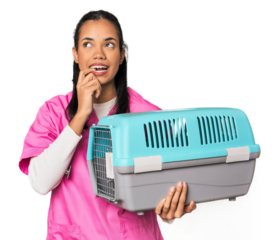 Young Filipina vet holding pet carrier relaxed thinking about something looking at a copy space.