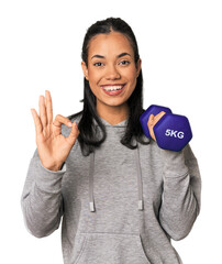 Young Filipina athlete with dumbbell cheerful and confident showing ok gesture.