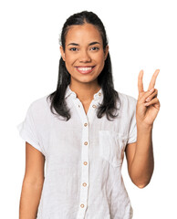 Young Filipina woman joyful and carefree showing a peace symbol with fingers.