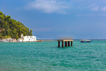 Vlacherna Monastery on the coast of Corfu, Greece, with boat passing by and clear blue waters