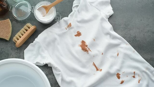 Preparation of dirty clothes for stain removal. Splashing cosmetic cream or foundation on a white t-shirt. Zero waste concept. top view