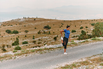 Obraz premium Determined Female Athlete Stretching After an Intense Run Through Rugged Mountain Terrain.
