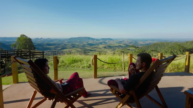 Relaxing Couple Enjoying Scenic Countryside View from a Porch. Peaceful Moment of a Couple Sitting on Chairs Overlooking a Beautiful Mountain View Landscape